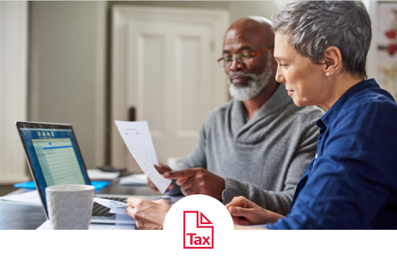 An older couple reviews their finances on their computer and with a print-out