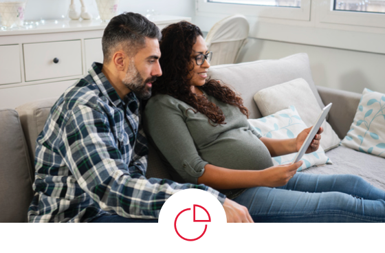 A pregnant woman and her husband look at their tablet together