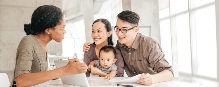 A Merrill advisor shows her tablet screen to a pregnant client and her wife.